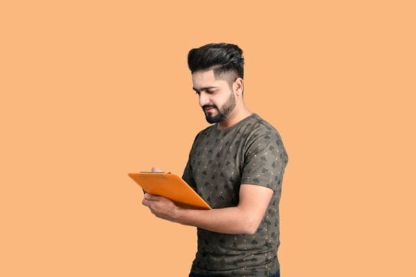 Student holding an exam preparation book for a competitive exam result update